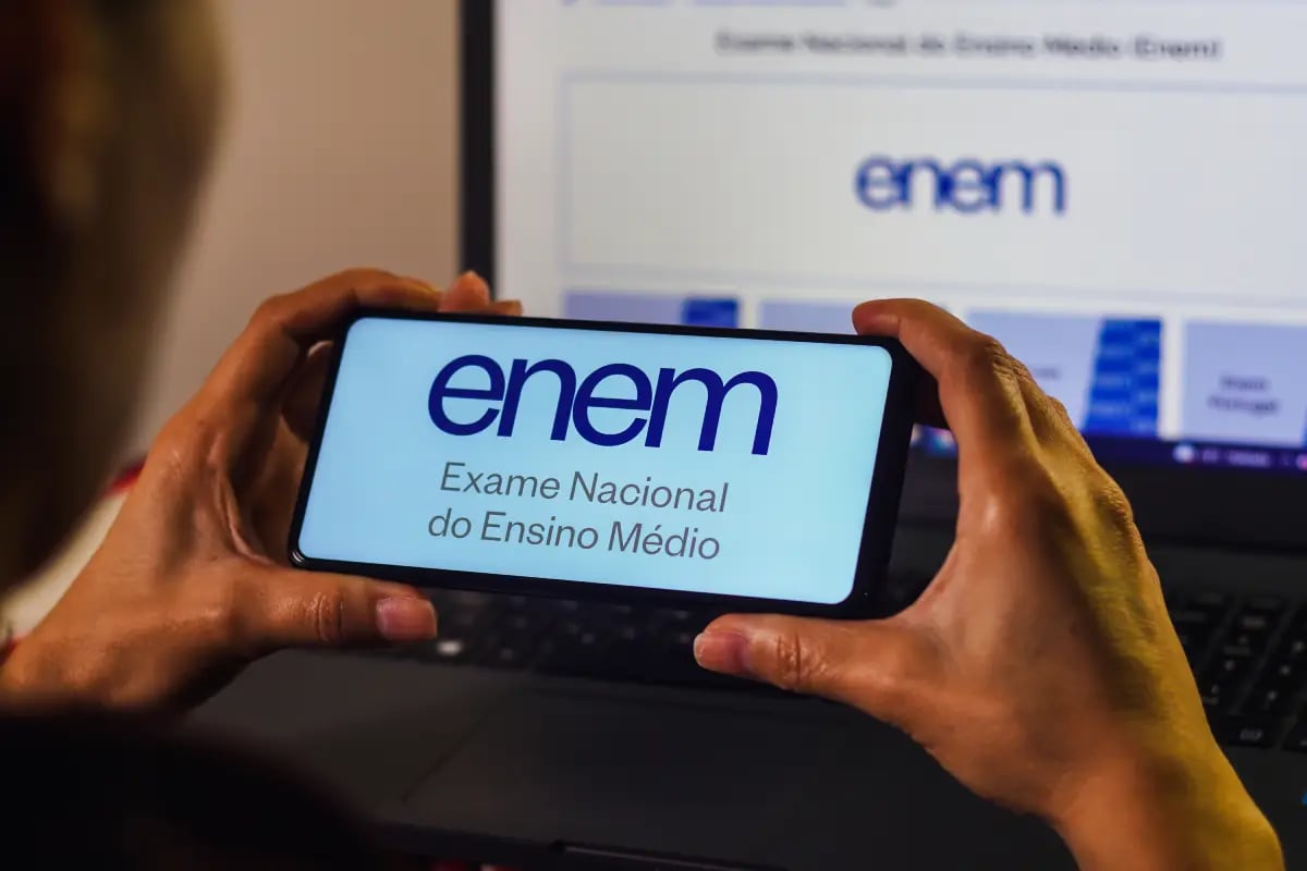 Como interpretar questões de matemática do Enem - jovem com celular em mãos analisando tela com logo do Enem